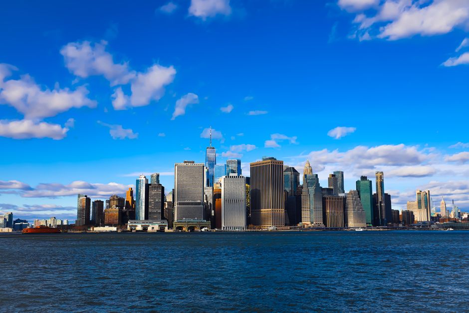 Panoramic view of New York City's iconic skyline against a clear blue sky, captured from across the water.