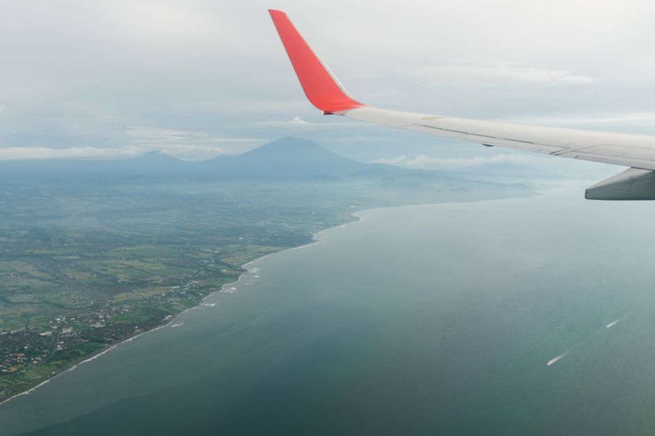 Amazing view from airplane window of aircraft wing and picturesque river flowing along green highlands against cloudy sky