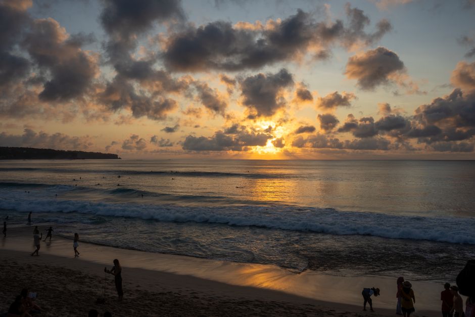 Stunning sunset view at Kuta Beach, Bali with silhouetted people along the shore.
