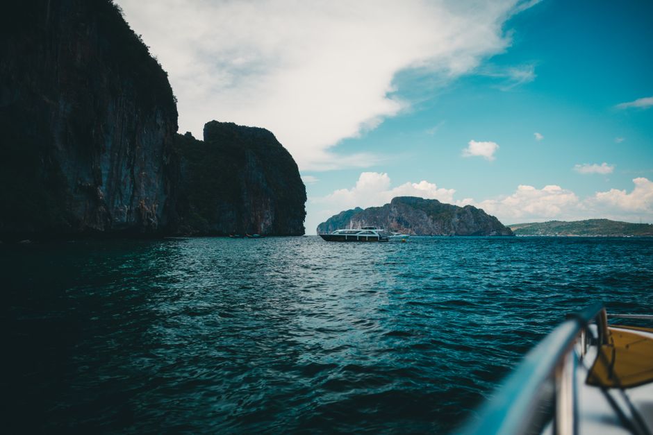 Experience a serene boat journey along Phuket's stunning rocky seascape under a clear sky.