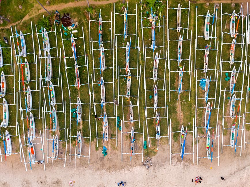 Aerial shot of traditional fishing boats lined up on a beach in Bali, Indonesia.