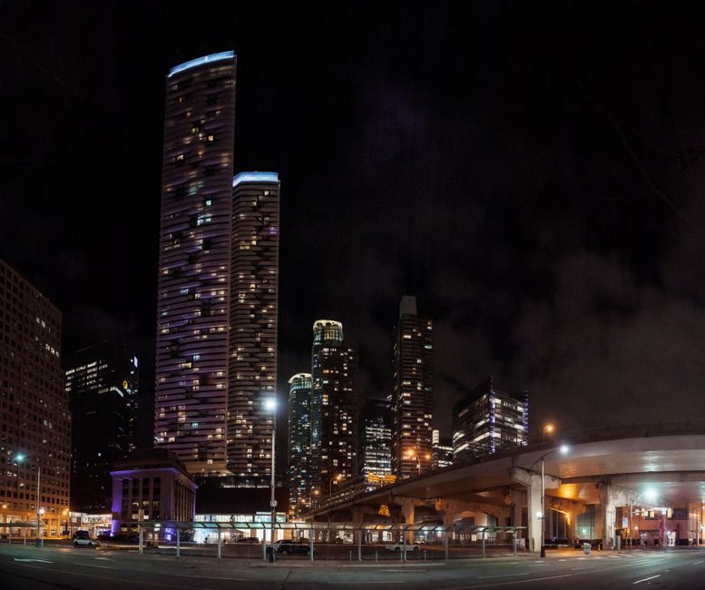 Vibrant city skyline with a view of illuminated skyscrapers and a bridge at night.