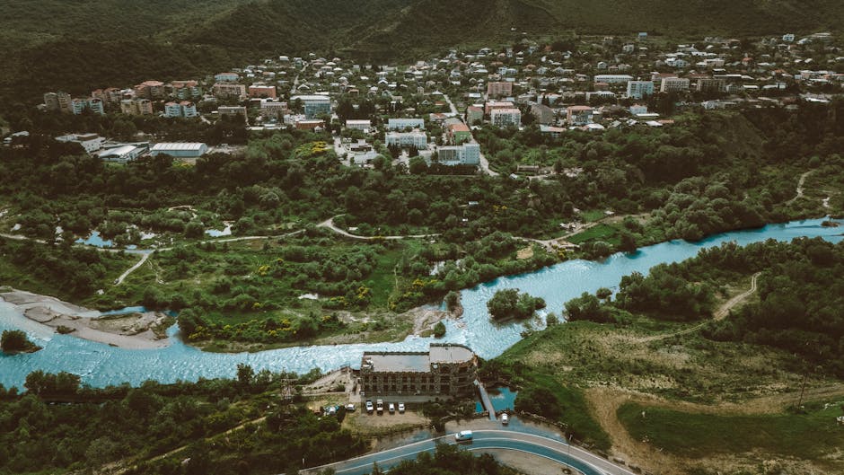 Stunning aerial view of a lush Georgian landscape with a river and town in the background.