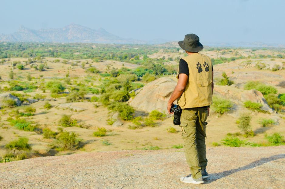 A man with a camera stands observing a vast rural landscape, showcasing natural beauty.