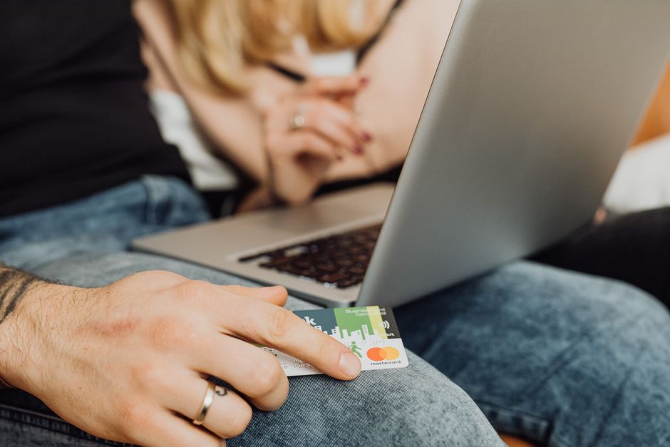 A couple using a laptop for online shopping, holding a credit card in a cozy setting.