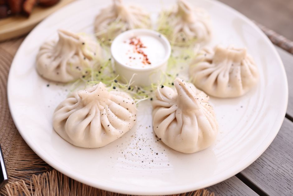 A close-up of tasty dumplings served with a creamy dipping sauce on a white plate.