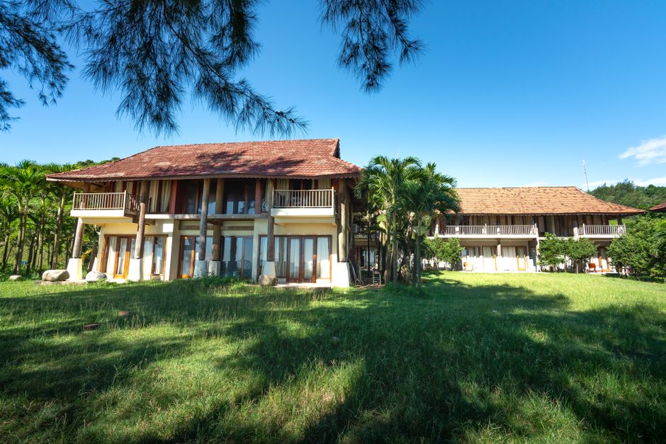 Charming tropical resort showcasing lush greenery and palm trees under a clear blue sky.