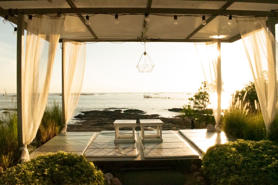 Enjoy a tranquil moment in a beachfront cabana overlooking Thailand's picturesque coast at sunset.