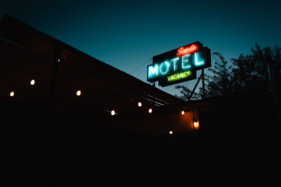 Atmospheric shot of a classic neon motel sign glowing in the evening light, indicating vacancy.