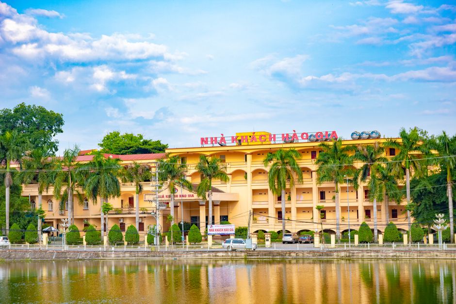 Charming hotel building with palm trees and pond reflection, ideal for travelers in Vietnam.