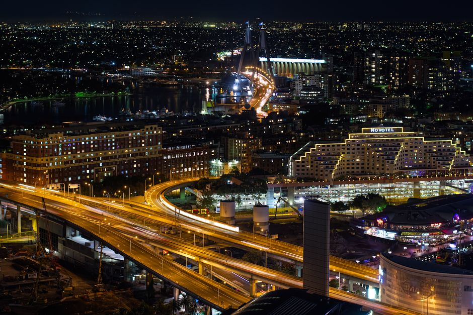 Illuminated Sydney skyline featuring the Anzac Bridge at night, showcasing vibrant city lights.