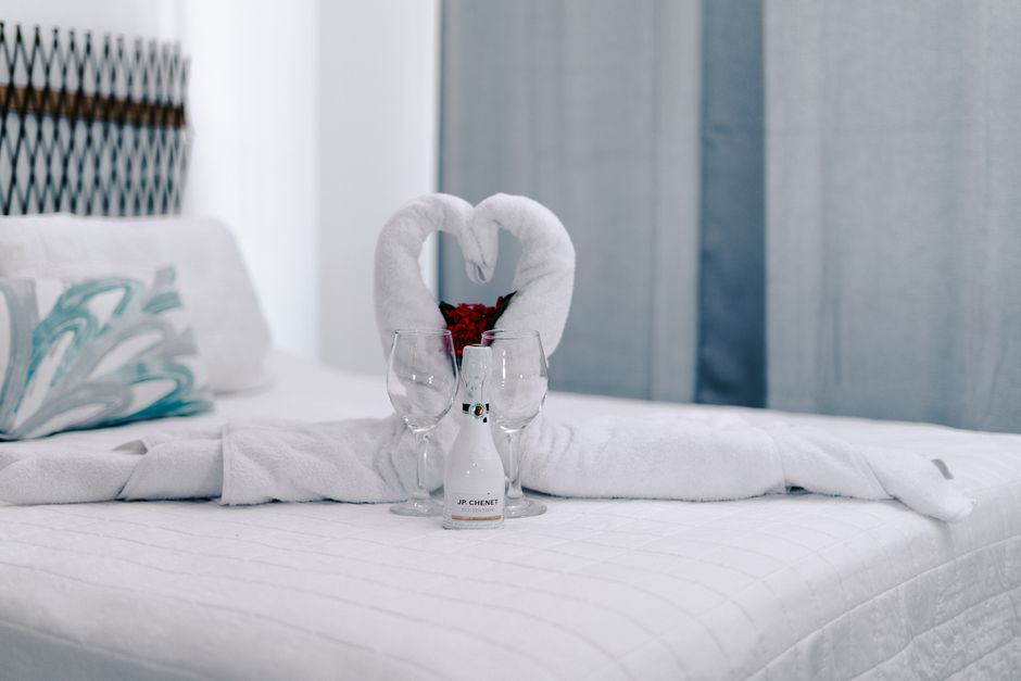 Elegant hotel room setup with towel swans, wine, and glasses creating a romantic atmosphere.