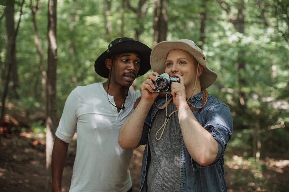 Young multiethnic male tourists with photo camera speaking in summer woods during trip in daylight
