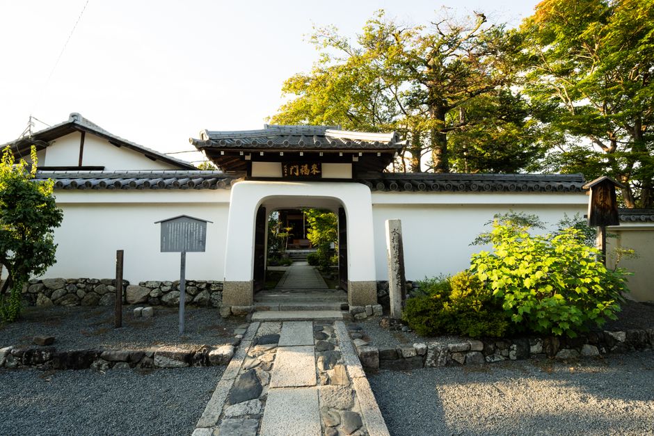 Beautiful traditional Japanese entrance gate surrounded by lush greenery in Kyoto, Japan.