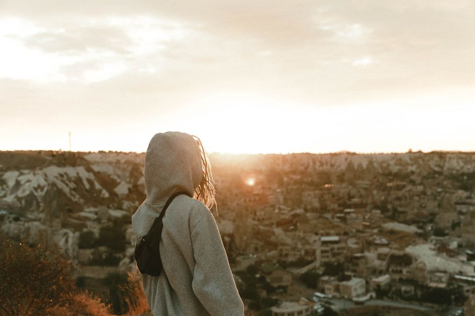 A woman in a hoodie overlooks the scenic sunset in Cappadocia, Turkey.