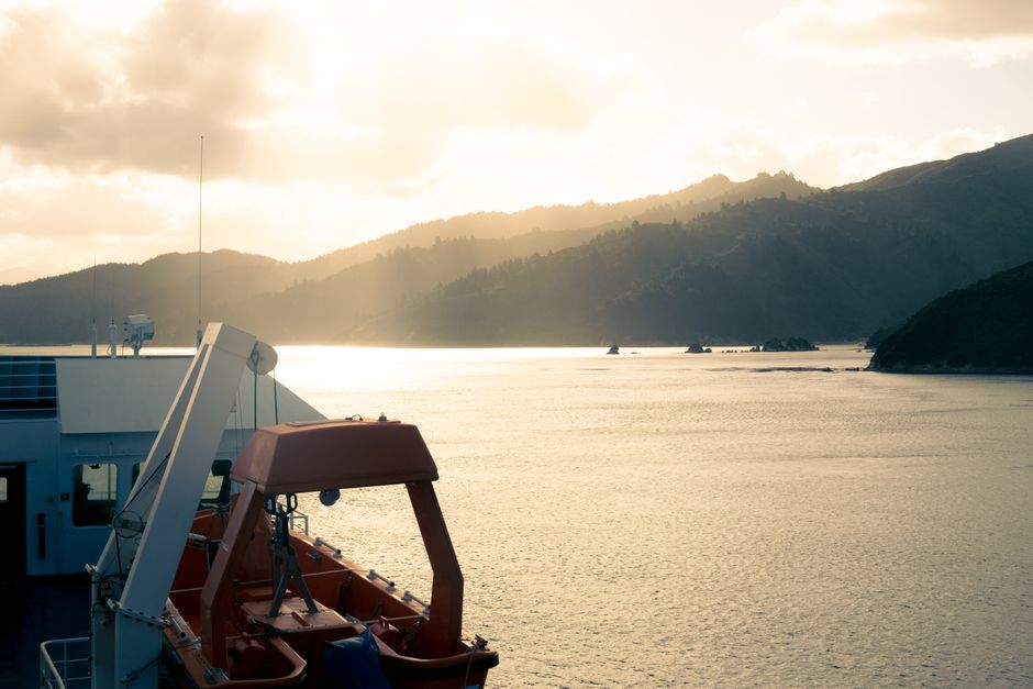 View of a ferry crossing at sunset in the tranquil Marlborough Sounds, New Zealand.