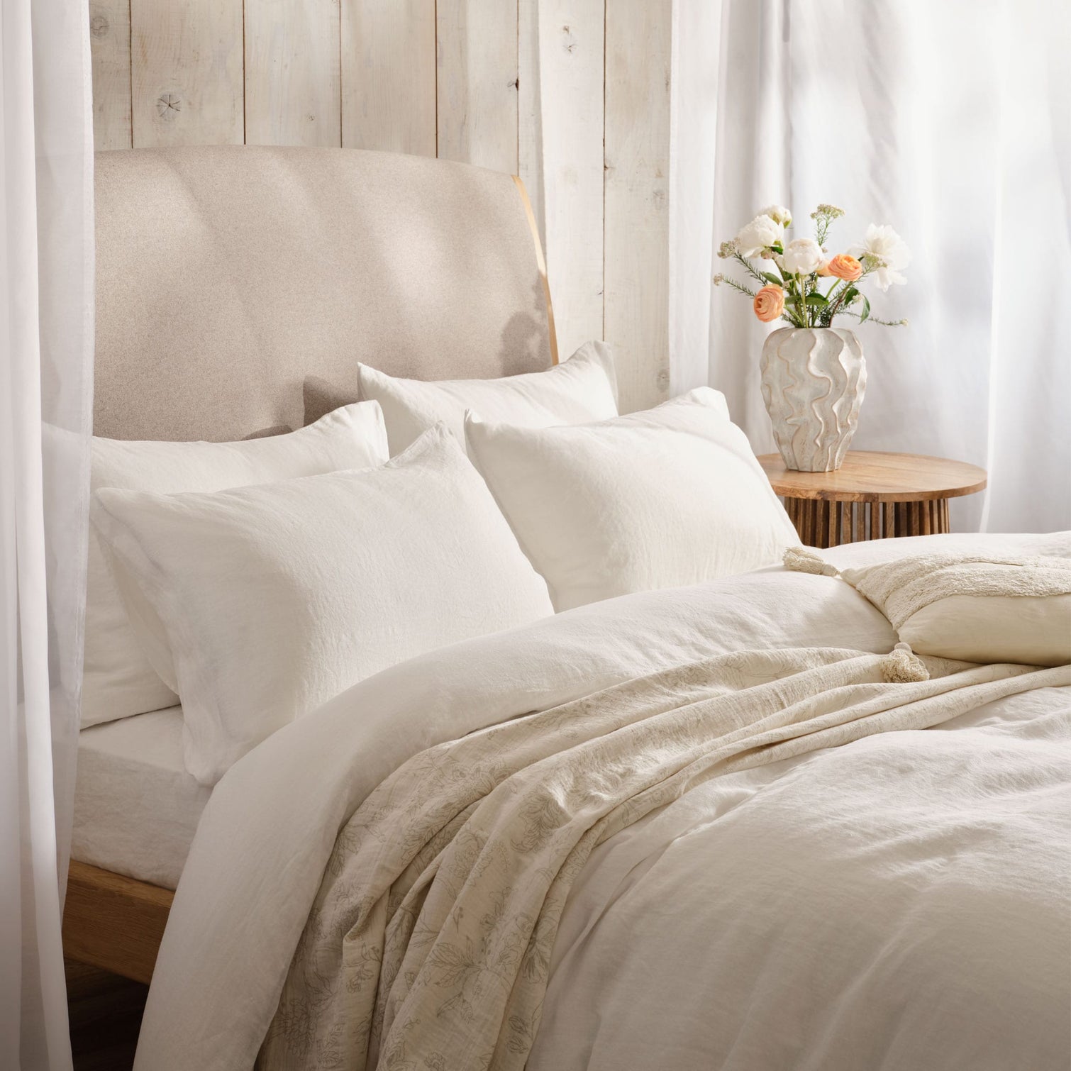 White linen bedding lit by summer window light