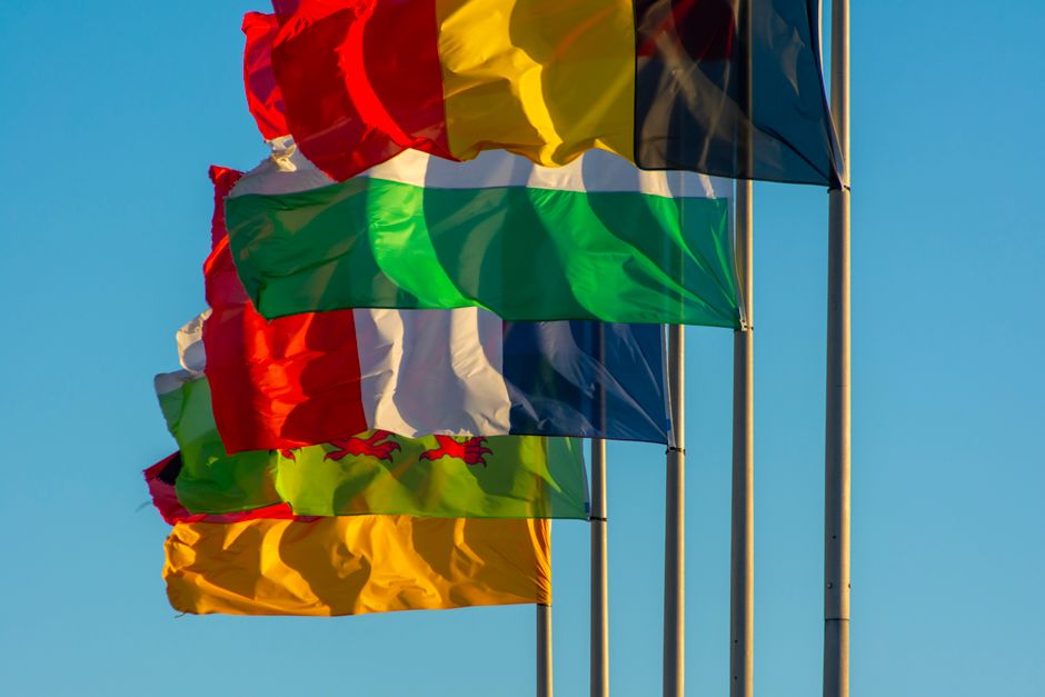 Vibrant national flags waving against a clear blue sky, symbolizing unity and diversity.