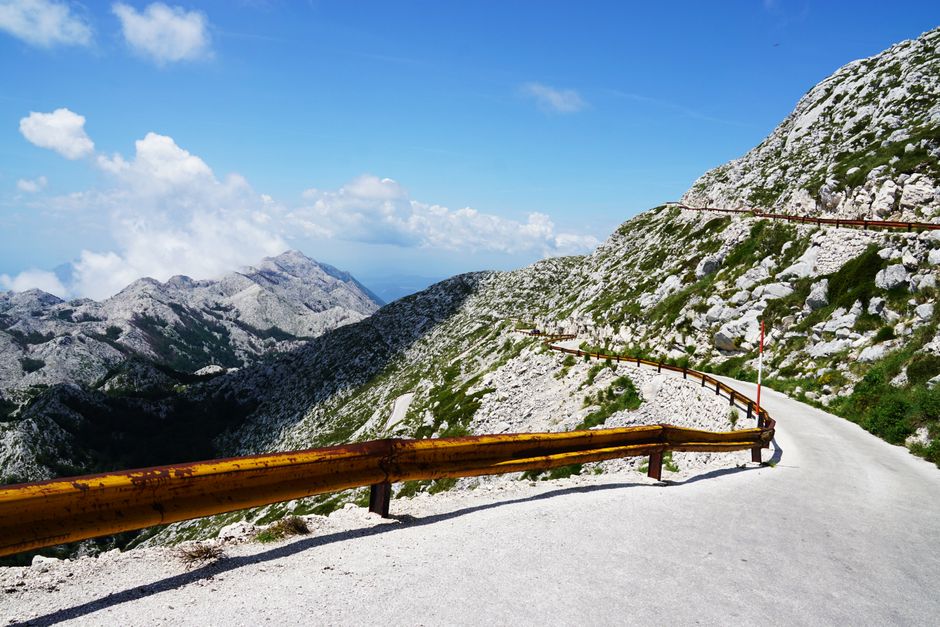 Winding road through a stunning mountain range on a clear, sunny day.
