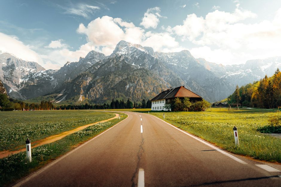 Picturesque road leading to mountains in Grünau im Almtal, Austria, under a bright sky.