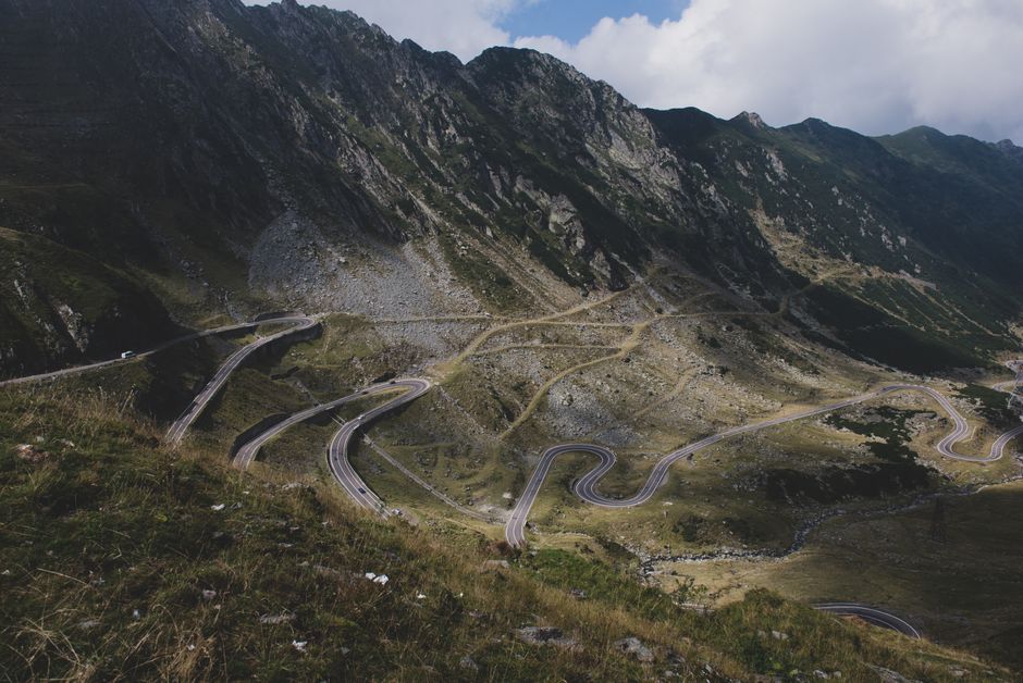 A scenic aerial view of the winding Transfăgărășan Highway through Romanian mountains.