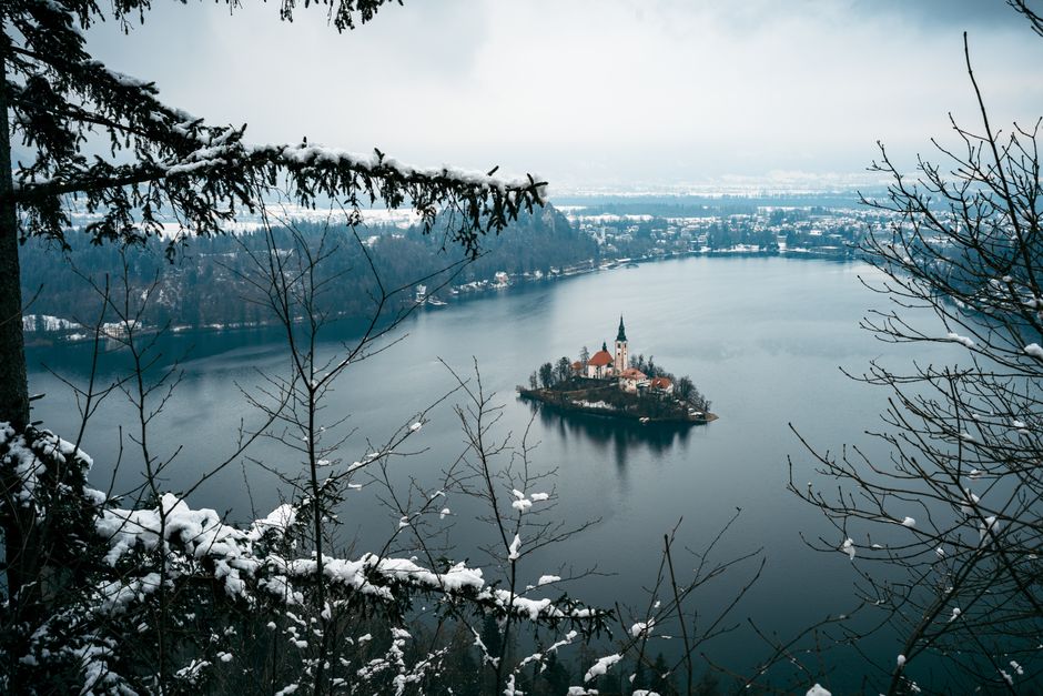Snowy landscape with a view of Lake Bled and its iconic church on an island.
