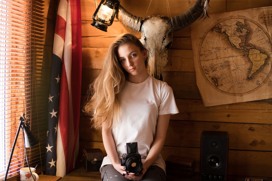 Woman holding camera in a rustic setting with vintage decor.