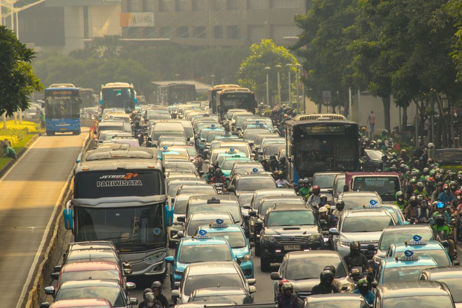 Bumper to bumper traffic scene capturing congested city street with buses, cars, and motorbikes.