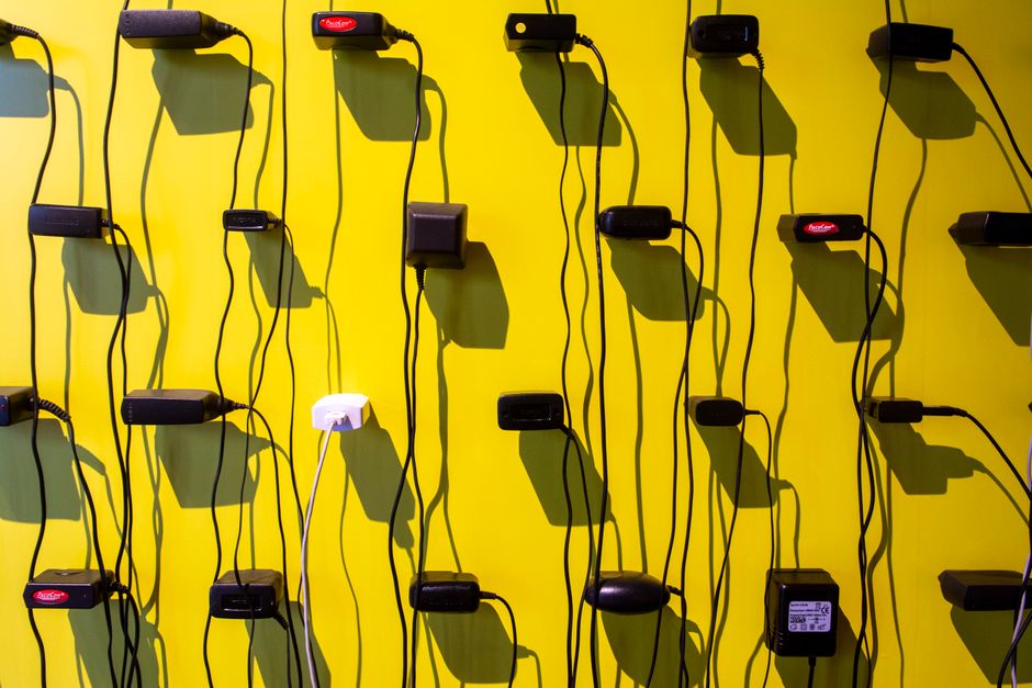 Power adapters casting shadows on a vibrant yellow wall, creating a geometric pattern.