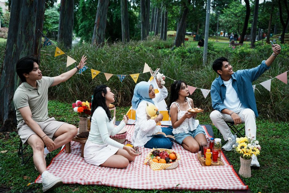 A group of friends having a picnic outdoors, capturing memories with a selfie.