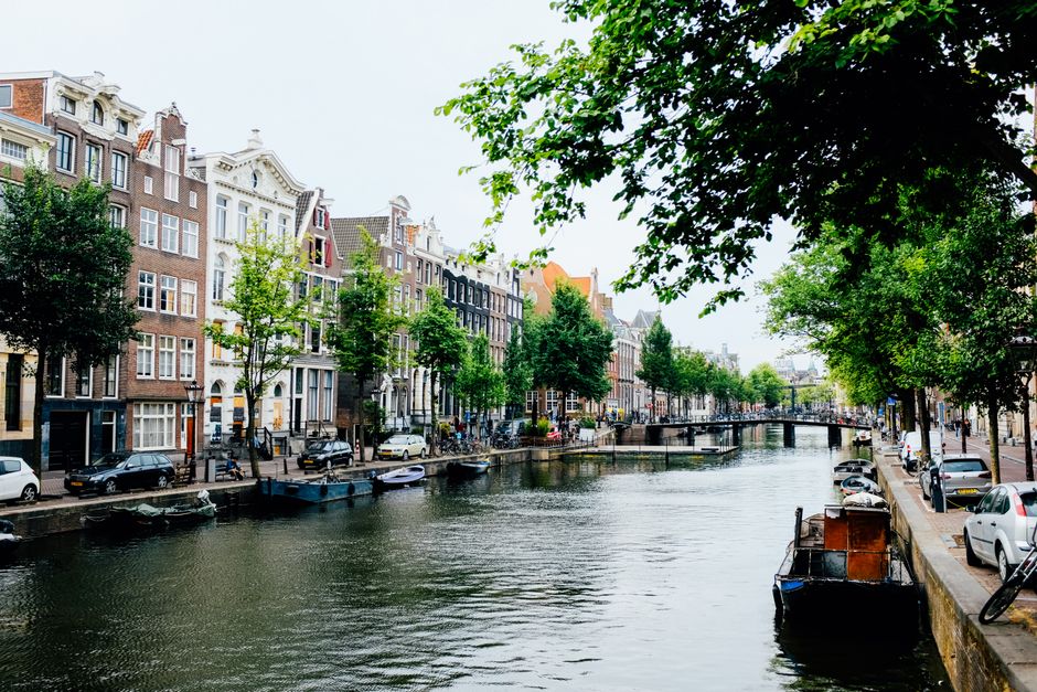 Exterior of small Dutch houses situated on canal shore in sunny spring Amsterdam