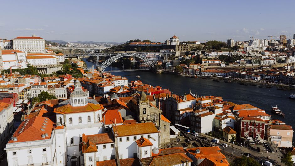 Stunning aerial view of Porto, Portugal featuring the historical Dom Luís I Bridge and red-roofed buildings.